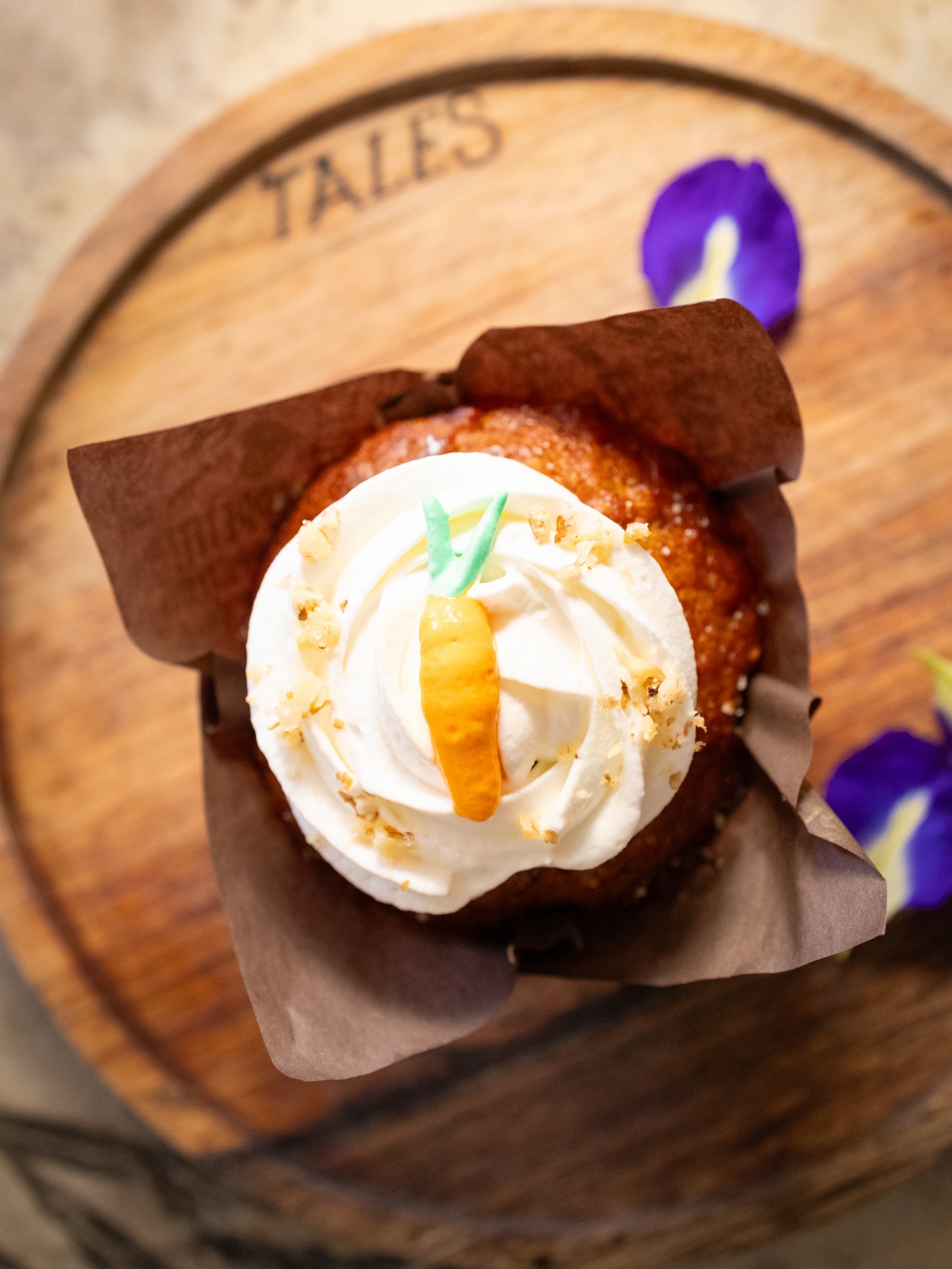 Carrot cupcake with cream frosting on a Tales branded wooden board